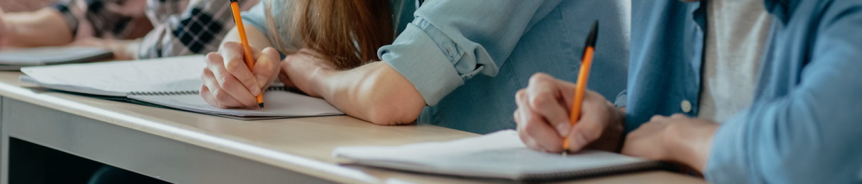 A student writing on an exam paper, preparing for their final math test.